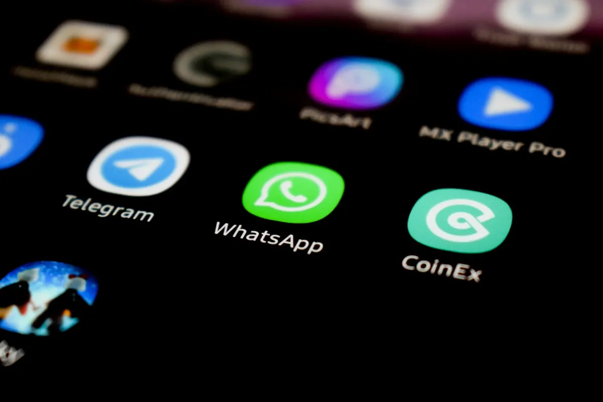Tela de celular em close mostrando o ícone do WhatsApp entre outros aplicativos de mensagem.