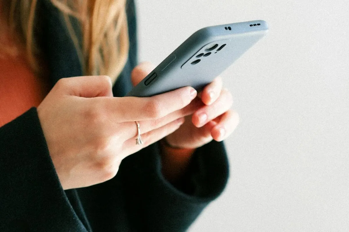 Mãos de uma cliente digitando no celular, como quem deixa uma avaliação para uma empresa no Google.