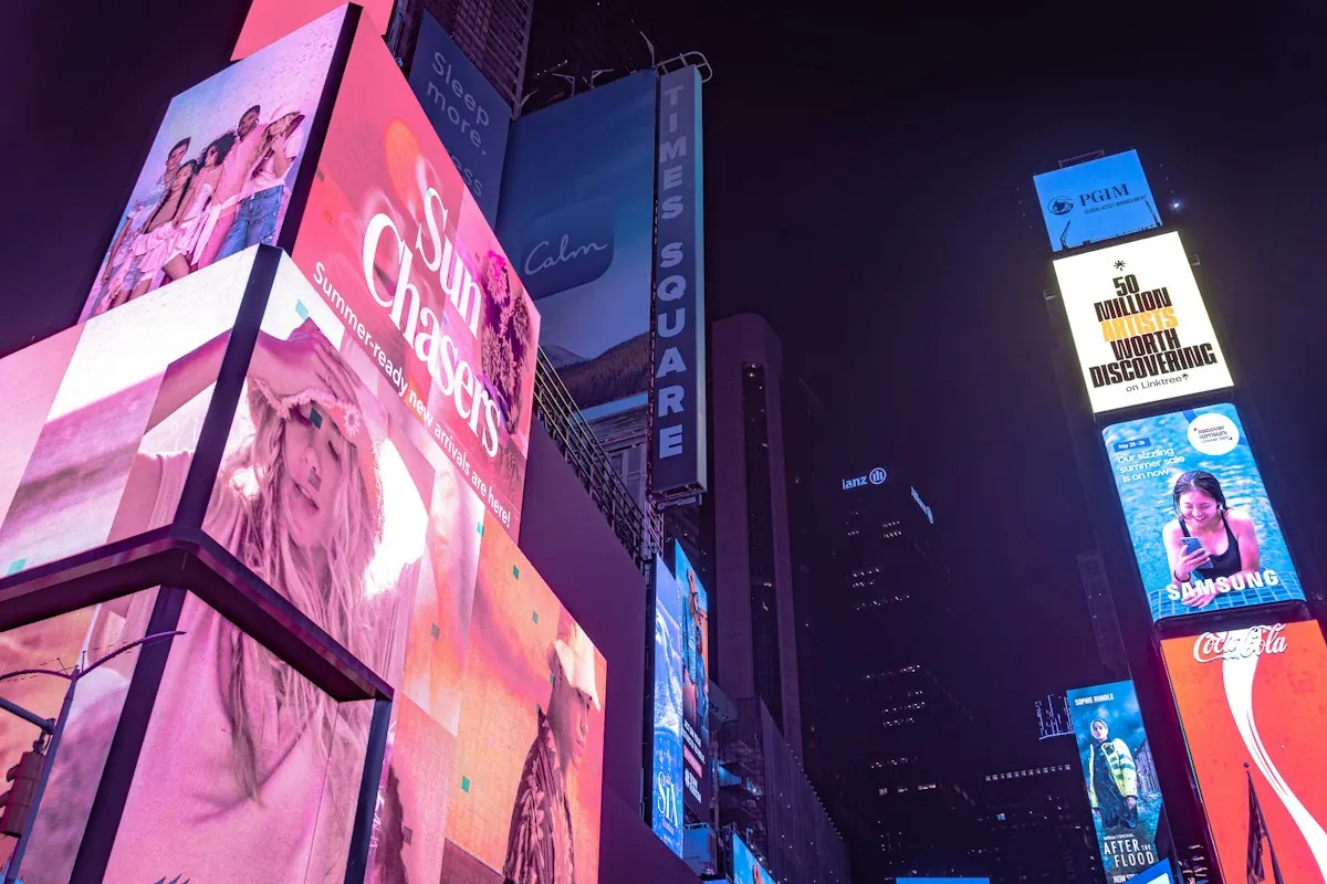 Telões de publicidade iluminados na Times Square, à noite, a vitrine física que lembra como o Google ganha dinheiro com anúncios.