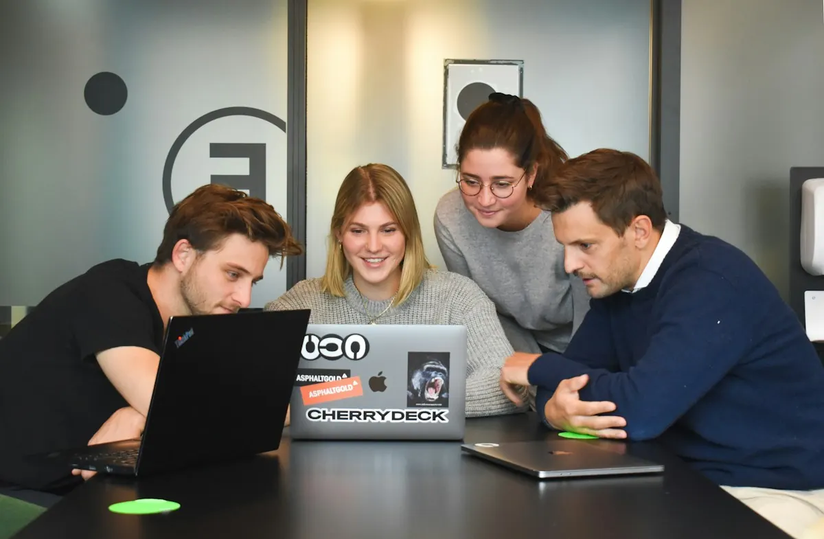 Pessoas colaborando em volta de um notebook, representando a parceria entre empresa e agência de tráfego pago.