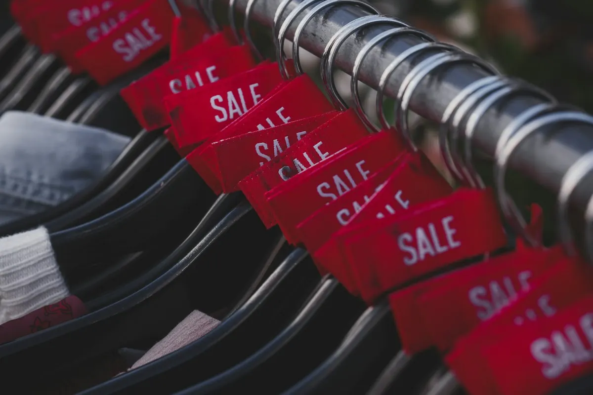 Etiquetas vermelhas de promoção em uma arara de roupas, exemplo clássico do gatilho mental da escassez.
