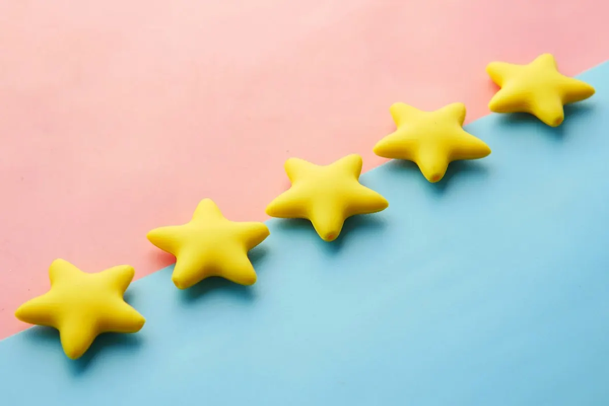 Cinco estrelas amarelas em linha sobre fundo rosa e azul, representando avaliações no Perfil da Empresa no Google.