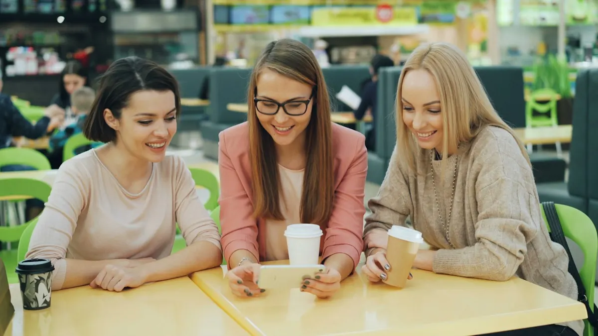 Três amigas rindo enquanto olham o mesmo celular, o momento em que um conteúdo de marketing viral é compartilhado.
