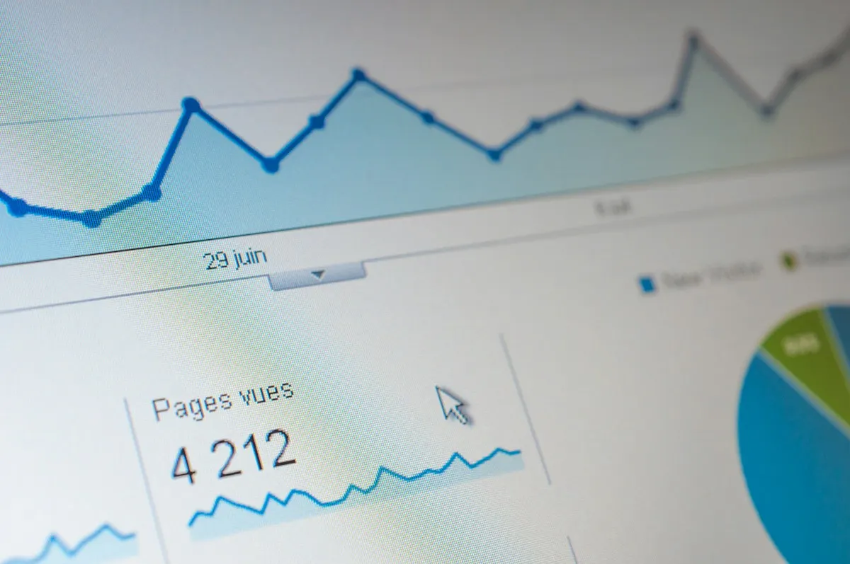 Tela de computador em close com um gráfico de linha azul e números de visitas de um relatório.