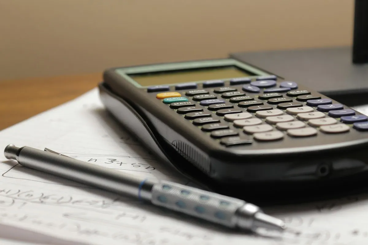 Calculadora e lapiseira sobre folhas com contas, como quem compara orçamentos de SEO.