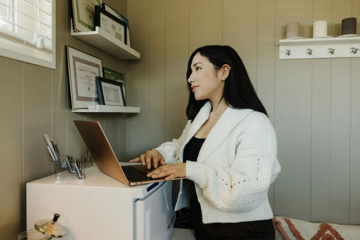 Empreendedora trabalhando no laptop em seu escritório, revisando o site institucional da empresa.