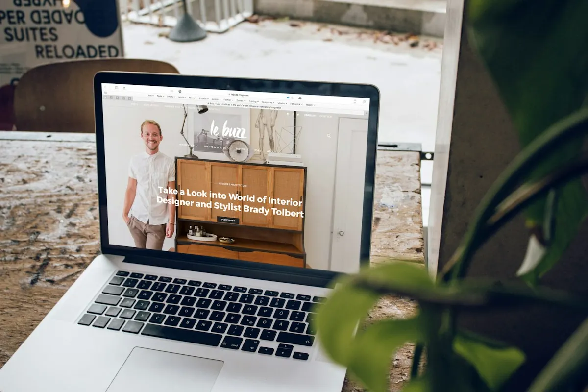 Exemplo de site institucional aberto em um MacBook sobre a mesa, com foto do profissional e chamada para conhecer o trabalho.