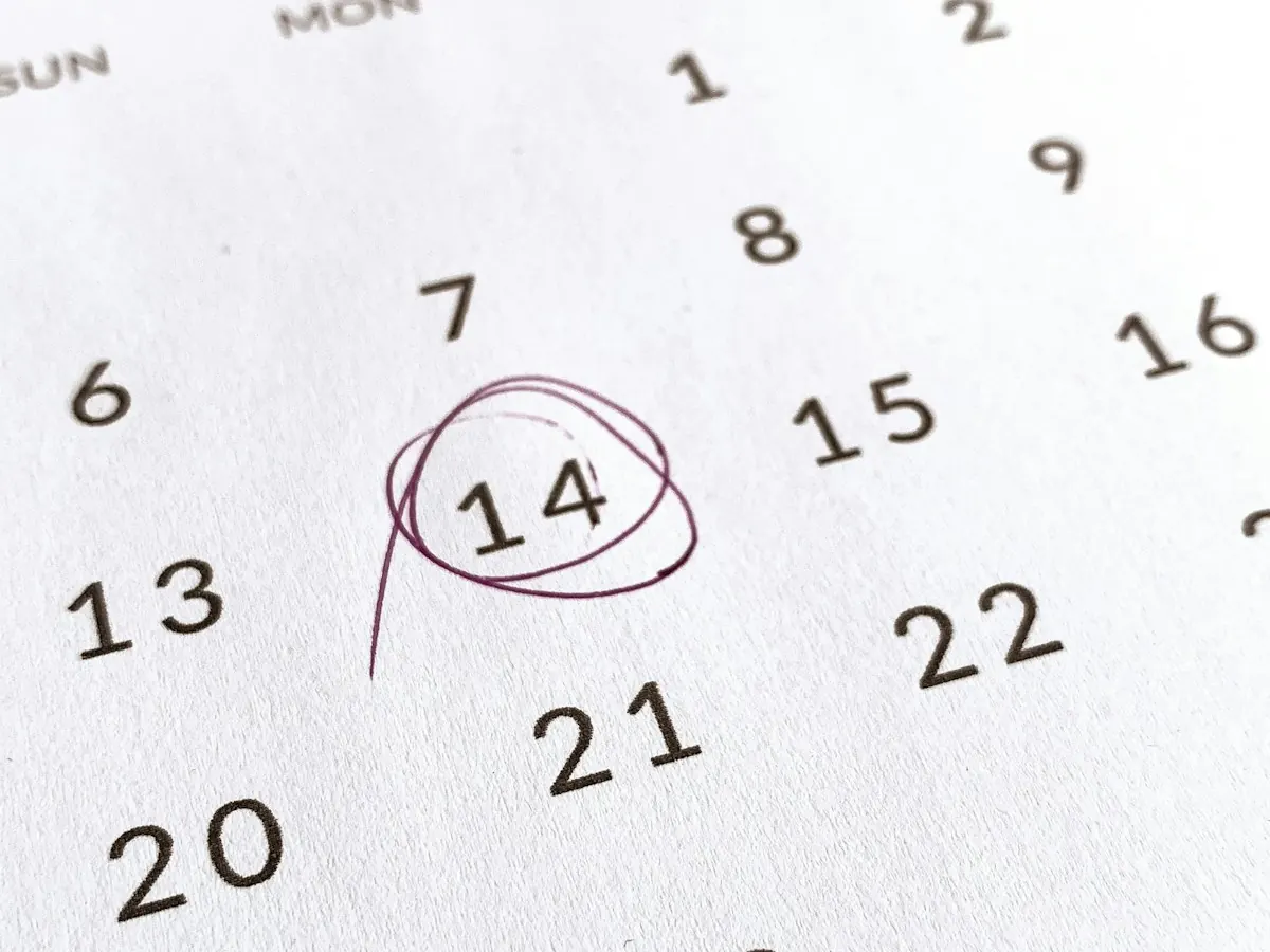 Calendário de papel com o dia 14 circulado à caneta.